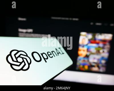 Cellulare con logo della società americana di intelligenza artificiale OpenAI LLC sullo schermo di fronte al sito web aziendale. Messa a fuoco a sinistra del display del telefono. Foto Stock