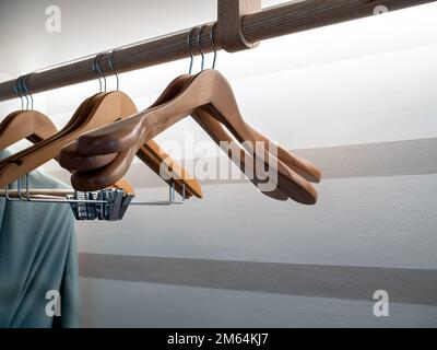 Appendiabiti di legno vuoti senza camicie o abiti appesi su un ripiano di stoffa di legno nel guardaroba su sfondo bianco parete preparazione per l'ospite che Foto Stock