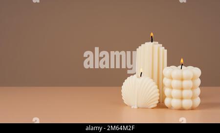 Cera d'oliva fatta a mano forme diverse candela bruciante su uno sfondo marrone beige. Candela vegana di sostenibilità, materiali naturali. Minimalista, accogliente Foto Stock