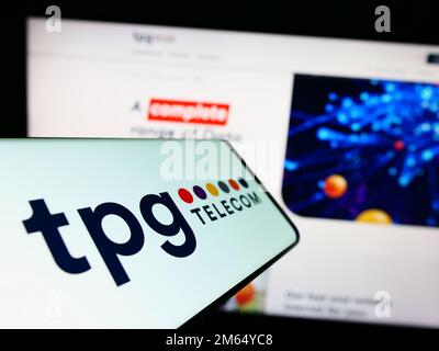 Cellulare con il logo della società australiana TPG Telecom Limited sullo schermo di fronte al sito web aziendale. Messa a fuoco al centro del display del telefono. Foto Stock