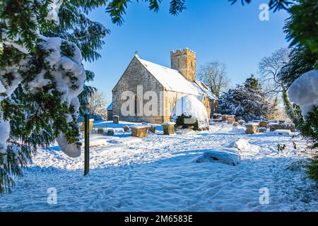 Neve d'inverno all'inizio della chiesa di St Michael & All Angels del 12th ° secolo nel villaggio di Cotswold di Bridpsfield, Gloucestershire, Inghilterra UK Foto Stock