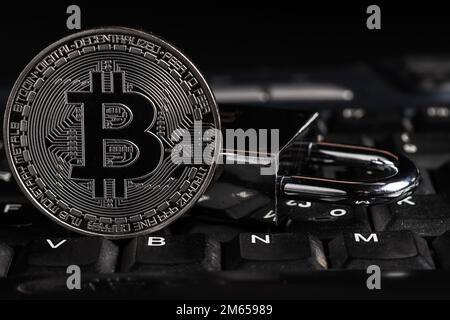 Concetto di sicurezza Bitcoin. Moneta argentata con lucchetto sulla tastiera del computer Foto Stock