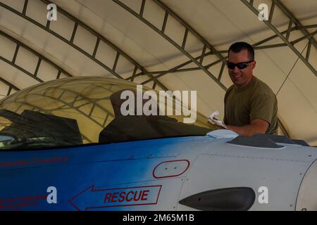 STATI UNITI Air National Guard Tech. Jonathan Lounsbery, 114th° capo equipaggio di manutenzione velivoli Squadron, pulisce la copertura di un F-16 durante il corso Weapons and Tactics Instructor (WTI) 2-22 alla Marine Corps Air Station Yuma, Ariz., 4 aprile 2022. WTI è un evento di formazione di sette settimane ospitato da Marine Aviation Weapons and Tactics Squadron One (MAWTS-1), che fornisce formazione tattica avanzata standardizzata e certificazione delle qualifiche di istruttore di unità per supportare la formazione e la preparazione dell'aviazione marina, e assiste nello sviluppo e nell'impiego di armi e tattiche aeronautiche. Foto Stock