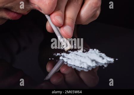 Concetto di tossicodipendenza.. Abuso di droghe, uomo che prende droghe, linee di russare di polvere di cocaina, primo piano. Foto Stock