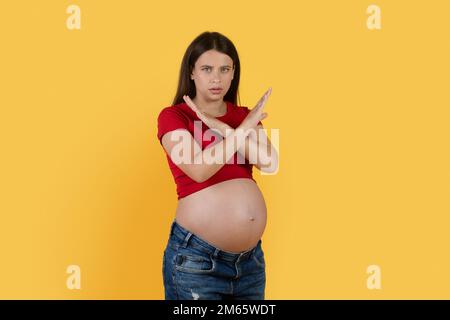 Giovane donna rignante che mostra un gesto di rifiuto con braccia incrociate su sfondo giallo Foto Stock