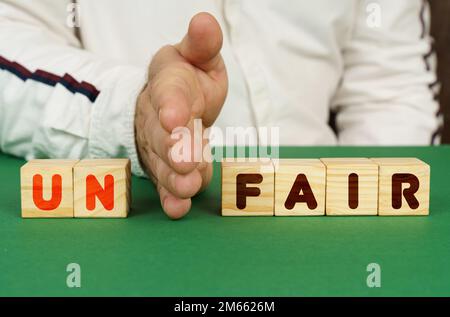 Concetto aziendale. Un uomo separa i cubi con l'iscrizione - un FAIR Foto Stock