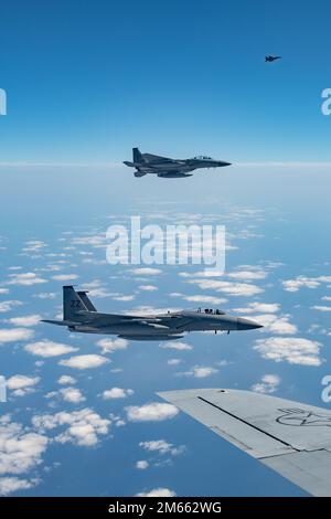 F-15C Eagles, assegnato al 44th Fighter Squadron, vola accanto all'ala di uno Squadrone di rifornimento aereo 909th KC-135 Stratotanker, durante un rifornimento aereo sull'Oceano Pacifico, il 5 aprile 2022. Il rifornimento aereo consente agli aerei di compiere la missione in modo efficiente, eliminando la necessità di tornare alla base per il carburante. Foto Stock