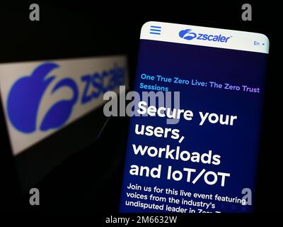Persona che tiene in mano uno smartphone con il sito Web della società statunitense di sicurezza sul cloud Zscaler Inc. Sullo schermo di fronte al logo. Messa a fuoco al centro del display del telefono. Foto Stock