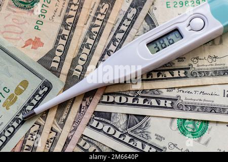 Un termometro sulla parte superiore di un mazzo di fatture del dollaro. Assistenza sanitaria, concetto di costo medico. Foto Stock