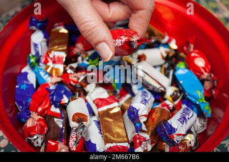 Mano che raggiunge in festeggiamenti scatola di cioccolato Foto Stock