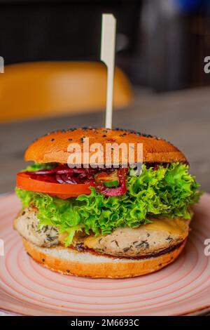 Primo piano hamburger arrosto e fresco con spiedino sul piatto nel ristorante. Hamburger di maiale o pollo alla griglia con panini croccanti, cipolla Foto Stock