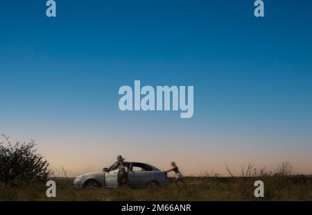 un incidente sulla strada, un'auto si è rotta, due belle ragazze modelli stanno spingendo l'auto per le riparazioni. Foto di alta qualità Foto Stock