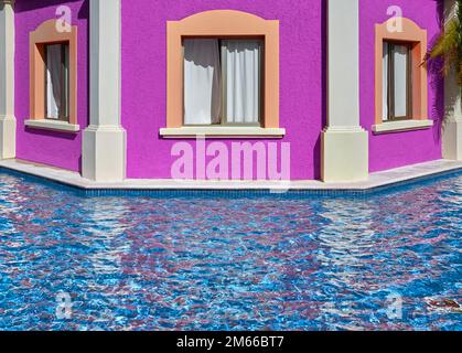 Edificio con facciata rosa con finestre vicino alla piscina. Foto Stock