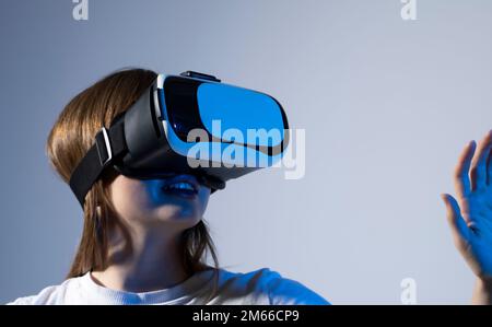 Tecnologie di realtà virtuale. Una giovane donna sicura in una cuffia per realtà virtuale che punta in aria. Foto Stock