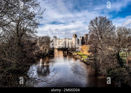 Vista sul castello di Warwick dal ponte alla luce del sole d'autunno Foto Stock