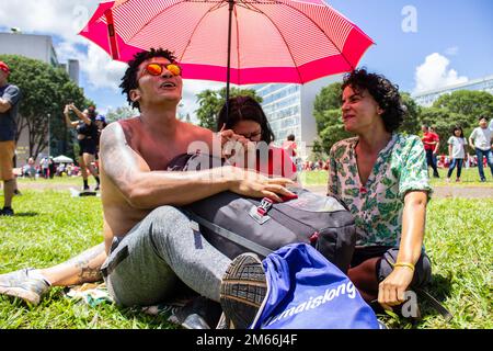 Brasília, DF, Brasile – 01 gennaio 2023: Tre persone si proteggono dal sole con un ombrello. Foto Stock