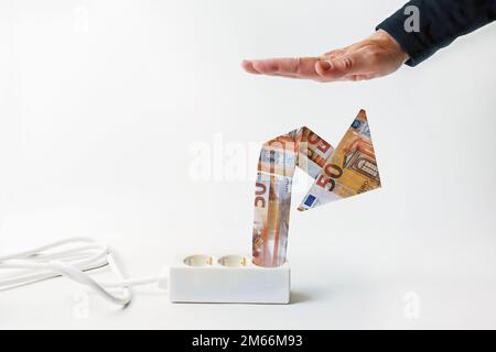 Striscia di potenza con freccia in aumento fatta di banconote in euro, mano dall'alto sta limitando la crescita dei prezzi durante la crisi energetica economica. Concetto di Price cap o Ger Foto Stock