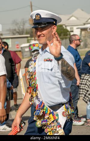 STATI UNITI Navy Petty Officer 2nd Class Casey Travers, Coast Guard Cryptologic Unit-Texas e Joint base San Antonio Fiesta Ambassador, cammina attraverso la Battle of Flowers Parade a San Antonio, Texas, 8 aprile 2022. La Battaglia dei Fiori rende omaggio agli eroi dell'Alamo, Goliad e della Battaglia di San Jacinto. È l'evento fondatore di Fiesta San Antonio e l'unica sfilata negli Stati Uniti prodotta interamente da donne, tutte volontarie. Foto Stock