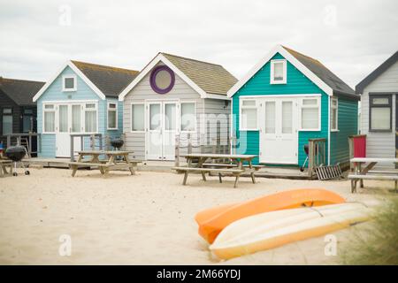 Colorate capanne in legno dipinte su una spiaggia di sabbia sul mare. Hengistbury Head, Dorest, Regno Unito Foto Stock