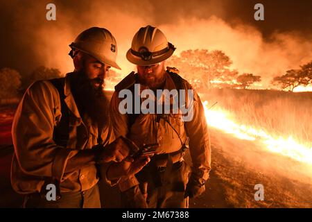 Dustin, a sinistra, e Cody, a destra, Texas state Forrest Service, Fredricksburg Task Force sciopero squadra vigili del fuoco discutere una mappa per gestire un grande incendio 9 aprile 2022 presso Joint base San Antonio - campo Bullis zona di demolizione gamma. JBSA-Camp Bullis comprende oltre 27.000 ettari di campi, aree di allenamento e terreni selvaggi sul lato nord di San Antonio ed è un punto di formazione fondamentale per i membri del servizio della base comune di San Antonio. Foto Stock