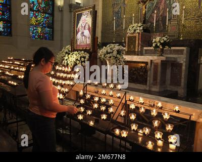 Manila, Filippine. 02nd Jan, 2023. Una donna accende una candela in onore del compianto Pontefice, il compianto Papa emerito Benedetto XVI. I devoti cattolici rendono il loro ultimo rispetto a Papa Emerito Benedetto XVI offrendo preghiere, illuminando candele e scrivendo il libro delle condoglianze per il pontefice tardivo nella Cappella di Cristo Re della Cattedrale di Manila lunedì 2 gennaio. Il defunto papa, il cui nome di nascita era Joseph Aloisius Ratzinger, morì all'età di 95 anni il 31 dicembre 2022 presso il Monastero Mater Ecclesiae nella Città del Vaticano. Credit: SOPA Images Limited/Alamy Live News Foto Stock