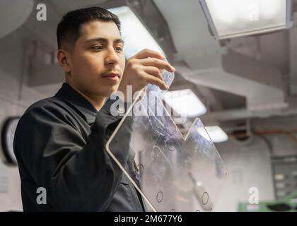 Aviazione meccanica strutturale Airman Apprentice Juan Villarreal, assegnato al dipartimento di manutenzione intermedia degli aeromobili della USS Gerald R. Ford (CVN 78), produce un cruscotto per chiodatura, il 10 aprile 2022. Ford è in corso nell’Oceano Atlantico per la conduzione delle qualifiche dei vettori e l’integrazione dei gruppi di sciopero come parte della fase di base su misura della nave prima dello spiegamento operativo. Foto Stock