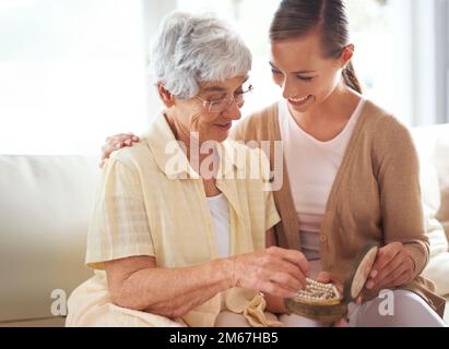 Questo è il loro heirloom di famiglia. Una donna anziana che dà a sua figlia una collana di perle. Foto Stock