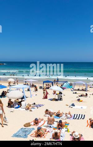 Persone che prendono il sole sugli asciugamani estate a Bondi Beach Sydney, cielo blu chiaro gennaio 2023, invitante oceano blu, Sydney, Australia Foto Stock