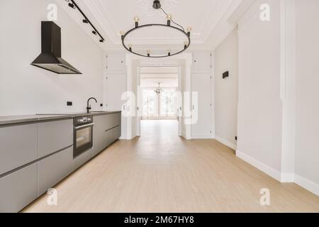 una cucina vuota con pareti bianche e pavimento in legno chiaro al centro della stanza è un chandel Foto Stock