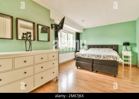 una camera da letto con pareti verdi e mobili bianchi nell'angolo, compreso un letto che è sulla parte superiore di un comò Foto Stock