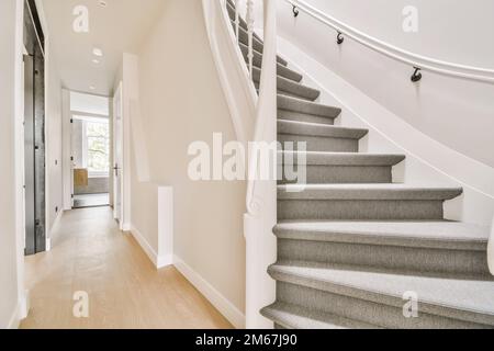 alcune scale in una casa con pavimento in legno chiaro e ringhiere bianche sul lato della scala che porta alla seconda Foto Stock