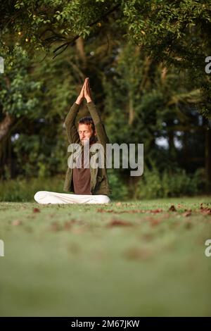 Raggiungere la trascendenza. un bell'uomo maturo che fa yoga all'aperto. Foto Stock
