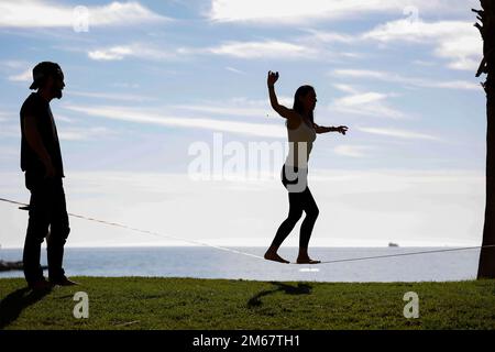 Silhouette di uomo che guarda la ragazza che cammina su una linea stanca a Malaga, Spagna, Europa Foto Stock