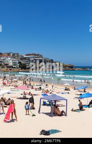 Bondi Beach a Sydney, estate giorno 2023, spiaggia affollata e la gente nell'oceano, cielo blu, sobborghi orientali di Sydney, NSW, Australia Foto Stock
