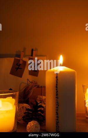 Candela con calendario dell'avvento tradizionale Burning Natale cera candele con i numeri che contano giù per Natale. Splendido Avvento a casa. Festive Candlelight e sfondo scuro. Vigilia di Natale Foto Stock