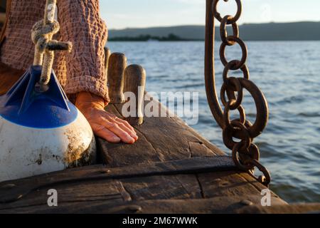 Primo piano di una mano di marinaio rugosa, navigando nel tramonto. Vela marina esperta in mare Foto Stock