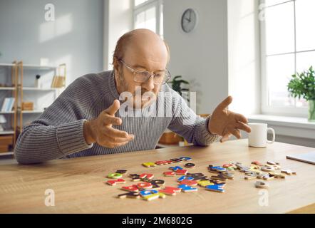 Anziano con malattia di Alzheimer seduto a tavola con alfabeto e le parole che compongono Foto Stock