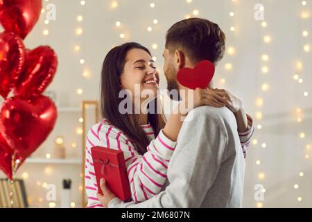 Coppia innamorata si abbracciano teneramente mentre si donano doni il giorno di San Valentino. Foto Stock