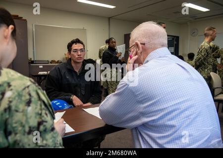 SASEBO, Giappone (14 aprile 2022) Seaman Memphis Kealohihaili, centro, di Waikoloa, Hawaii, assegnato alla nave d'assalto anfibio USS America (LHA 6), schierata a suo tempo, parla al comandante in pensione Randy Miller, capo di Kansas City, Mo., assegnato al Fleet Engagement Team del comando del personale della Marina, Informazioni sulla nuova tariffa di Kealohihaili come specialista delle operazioni durante un tirocinio professionale Career Track Rodeo nella cappella di base a bordo degli Stati Uniti Attività della flotta Sasebo. Il team NPC Fleet Engagement si è recato da Millington, Tennessee, per incontrare PACT Sailors st Foto Stock