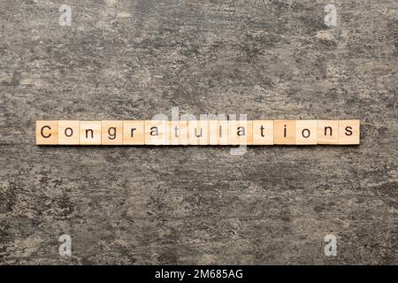 congratulazioni parola scritta su legno blocco. complimenti testo su cemento tavolo per la vostra desing, concetto. Foto Stock