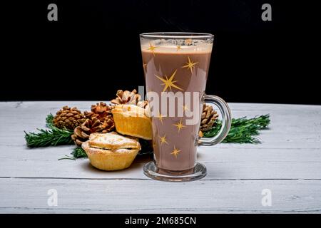 Festive bicchiere di cioccolato seduto con pronto a mangiare le torte di Natale Foto Stock