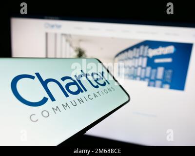 Telefono cellulare con il logo della società americana di media Charter Communications Inc. Sullo schermo di fronte al sito web. Messa a fuoco al centro a sinistra del display del telefono. Foto Stock