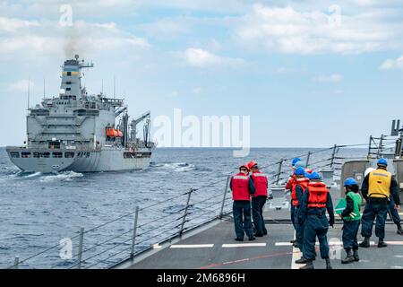 MARE DELLE FILIPPINE (17 aprile 2022) i marinai preparano le loro stazioni come il cacciatorpediniere di missili guidati di classe Arleigh Burke USS Spruance (DDG 111) viene accanto al comando militare Sealift rifornimento della flotta di oliatore USNS Tippecanoe (T-AO 199) per un rifornimento in mare. Abraham Lincoln Strike Group è in fase di implementazione pianificata nell'area delle operazioni della flotta 7th degli Stati Uniti per migliorare l'interoperabilità attraverso alleanze e partnership e al tempo stesso fungere da forza di risposta pronta a sostegno di una regione indomPacifico libera e aperta. Foto Stock