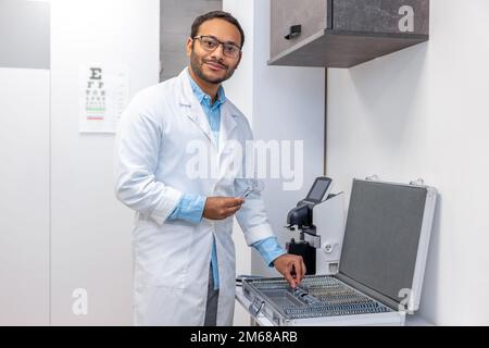 Medico di sesso maschile in camice da laboratorio in piedi la scatola con attrezzatura optometrica Foto Stock