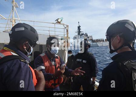 Figi Navy Ens. Peni Koroitubuna discute la procedura con un team composto da funzionari delle forze dell'ordine delle Fiji e degli Stati Uniti Membri dell'equipaggio della Guardia di costa Cutter Munro durante l'imbarco di un peschereccio con bandiera cinese al largo della costa delle Fiji, 18 aprile 2022. Un team di cinque poliziotti delle Fiji ha lavorato con l’equipaggio di Cutter Munro nell’aprile 18-19 come parte dell’operazione Blue Pacific, che mira a contrastare la pesca illegale, non dichiarata e non regolamentata, e a rafforzare le relazioni per rafforzare la sovranità marittima e la sicurezza in tutto l’Indo-Pacifico. Foto Stock