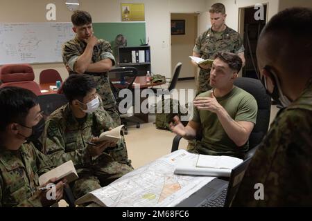 STATI UNITI Marines, 5th Air Naval Gunfire Liaison Company (5th ANGLICO), III Marine Expeditionary Force (III MEF), con membri della Japanese Ground Self-Defense Force (JGSDF) Amphibious Rapid Deployment Brigade (ARDB), si scambiano feedback su un esercizio di comunicazione, il 18 aprile 2022, su Camp Hansen, Okinawa, Giappone. I membri del servizio ARDB hanno completato missioni simulate di supporto antincendio e aereo per prepararli a chiamare gli aerei americani e il supporto antincendio in un ambiente operativo. Foto Stock