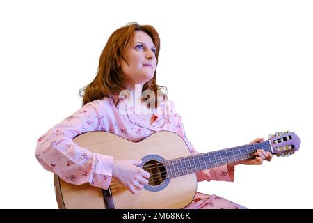 Una giovane musicista lavora da casa, isolata su sfondo bianco. Una donna con una chitarra conduce lezioni online. Un insegnante di musica conduce un onli Foto Stock