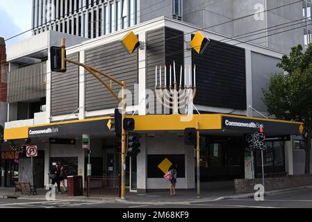 Il ramo della Commonwealth Bank, all'angolo tra Glen Huntly Rd e Orrong Rd, con un grande menorah in cima al suo tetto, che segna la vacanza ebraica di Chanukah Foto Stock