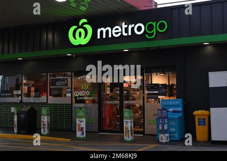 Il minimarket Woolworths MetroGo, adiacente ad un distributore di benzina Ampol, con un luminoso cartello verde Foto Stock