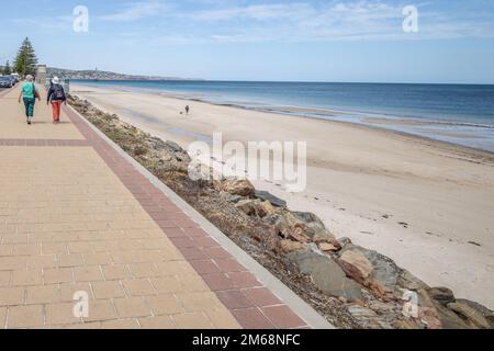 Due donne che camminano lungo il marciapiede accanto al mare in una giornata estiva Foto Stock